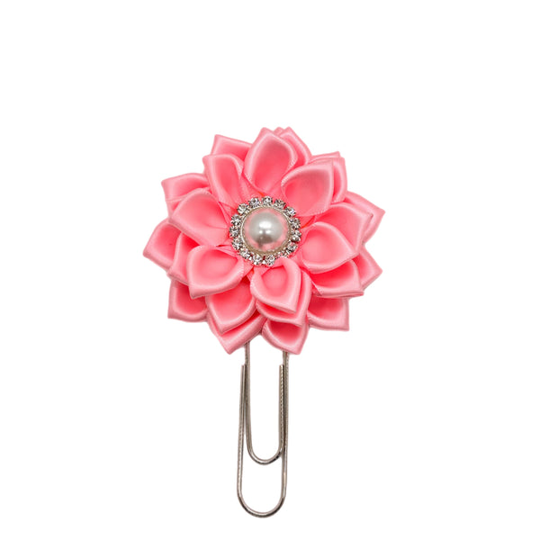 Pink flower-shaped clip with a pearl center on a white background