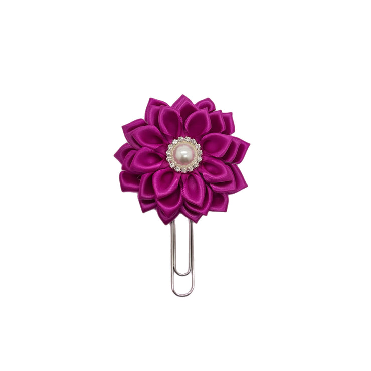 Purple flower-shaped clip with a pearl center on a white background