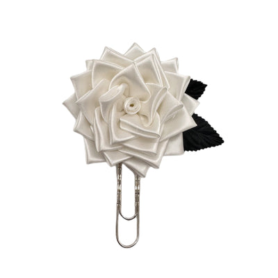 White flower-shaped clip with black accents on a white background