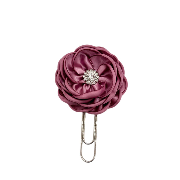 Purple flower-shaped hair clip with a rhinestone on a white background