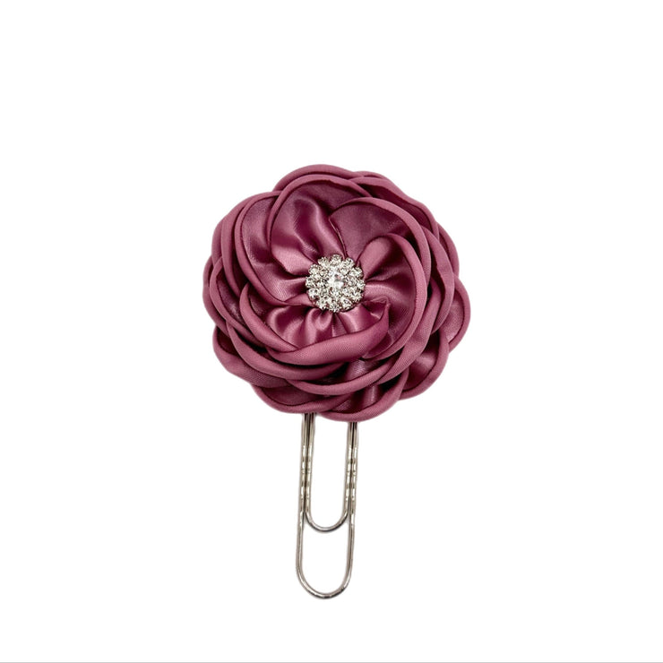 Purple flower-shaped hair clip with a rhinestone on a white background