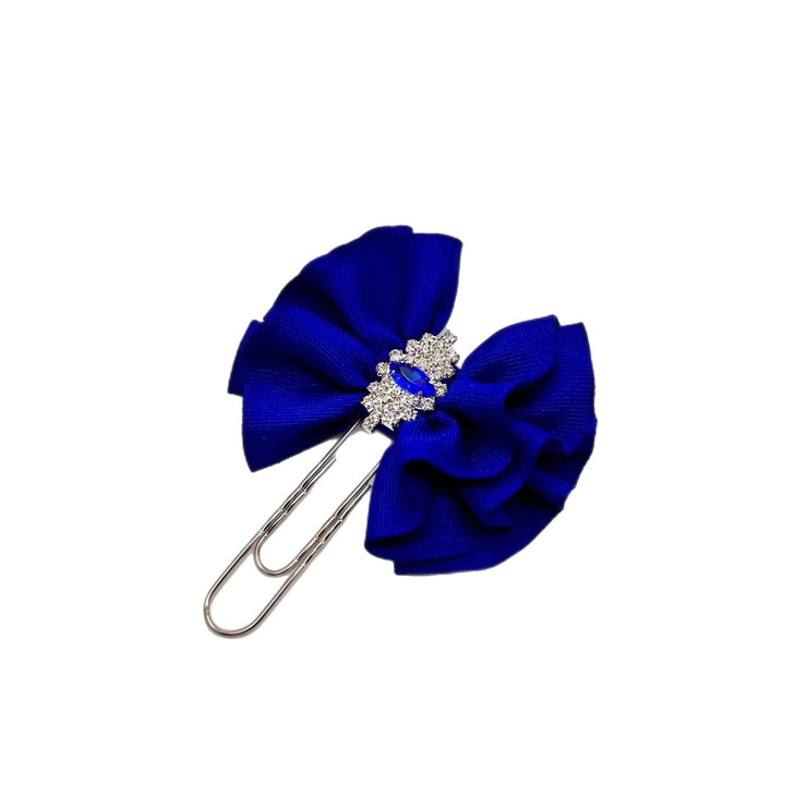 Blue bow hair clip with a decorative center on a white background.